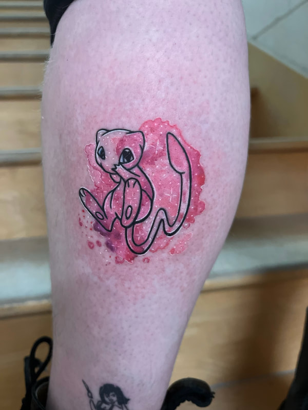 Pink watercolor Mew Pokémon tattoo on a woman's leg.