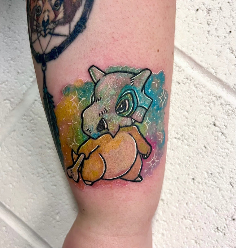 Rainbow watercolor Cubone Pokémon tattoo on an arm.